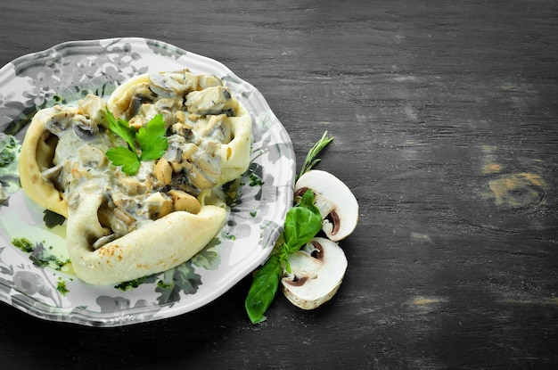 Frittelle con funghi, formaggio e salsa di panna su uno sfondo di legno vista dall'alto spazio libero per il testo