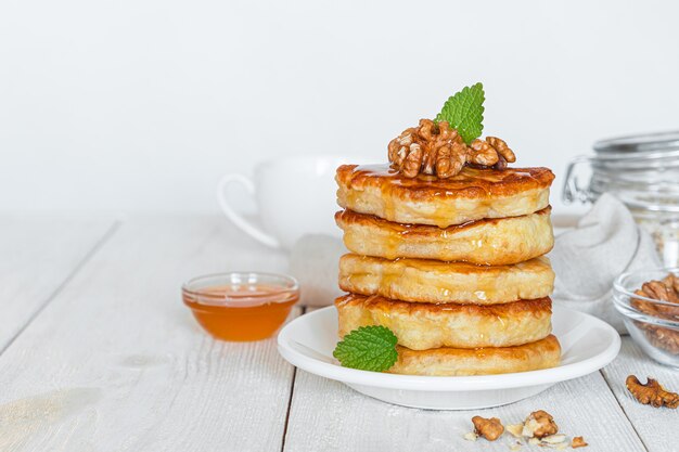 Pancakes with nuts, honey and nuts on a white background with space to copy. Side view.