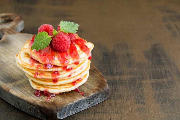  pancakes with raspberry on a dark background.