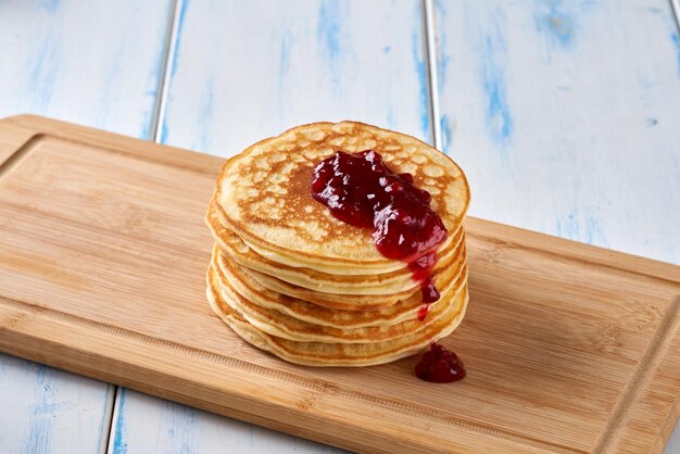 Pancakes with red berry jam on the wooden table