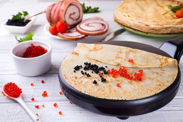 Pancakes with red caviar on plate.