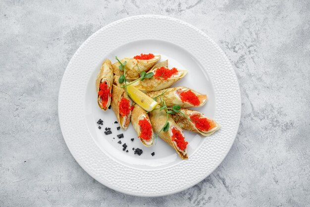 Pancakes with salmon cream cheese and Tobiko caviar on a white background