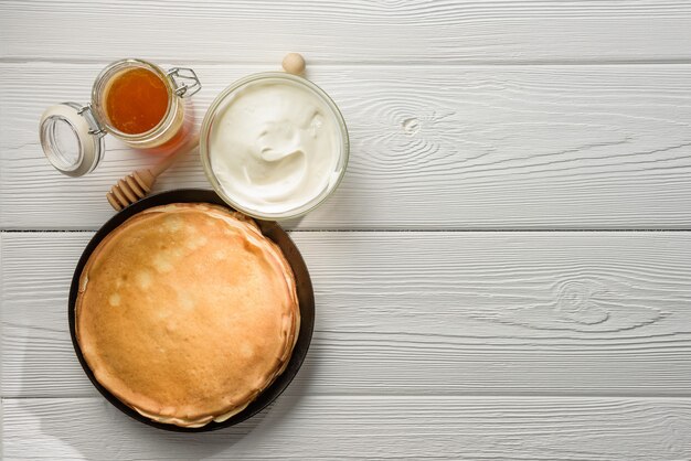 Pancakes with sour cream and honey on the table