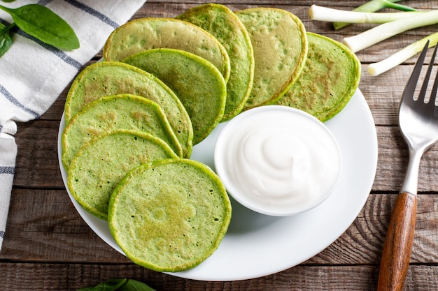 Frittelle con spinaci e panna acida su un tavolo di legno