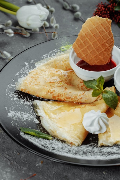 Pancakes with strawberries and creme black plate.