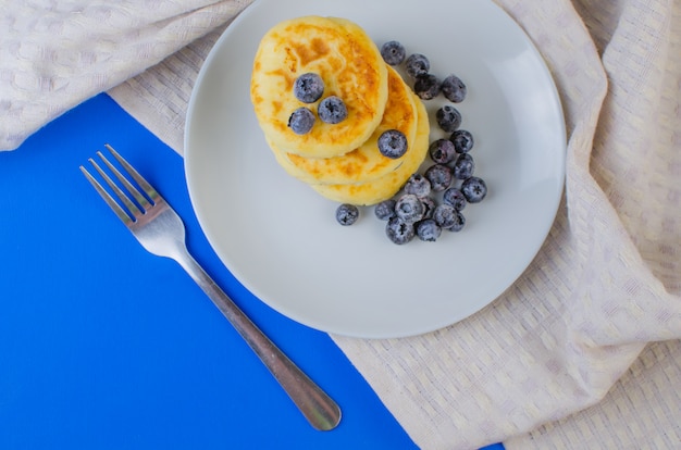 Pancake con fragole, lamponi, mirtilli su una superficie blu