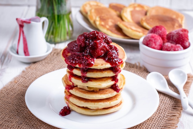 Photo pancakes with strawberry and jam on plate on white wooden background. stack of pancakes on the table