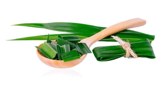 Foglia e fetta di pandan in cucchiaio di legno isolato su bianco per avere un sapore e un aroma in alimento dell'asia con il percorso di ritaglio.