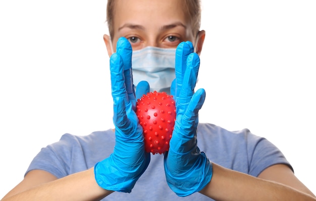 Pandemic covid-19 theme. Woman in protective gloves, medical face mask holds a virus strain model isolated on white.