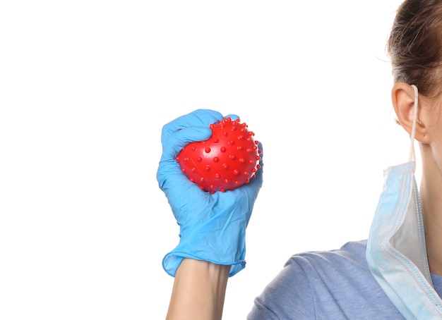 Pandemic covid-19 theme. Woman in protective gloves, medical face mask holds a virus strain model isolated on white.