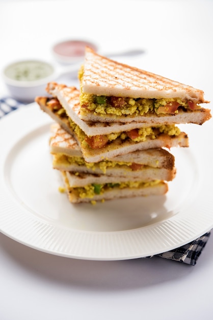 Paneer bhurji sandwich is een smakelijk gerecht op basis van paneer gemaakt met kwark. Geserveerd met verse tomatenketchup en groene muntchutney. selectieve focus