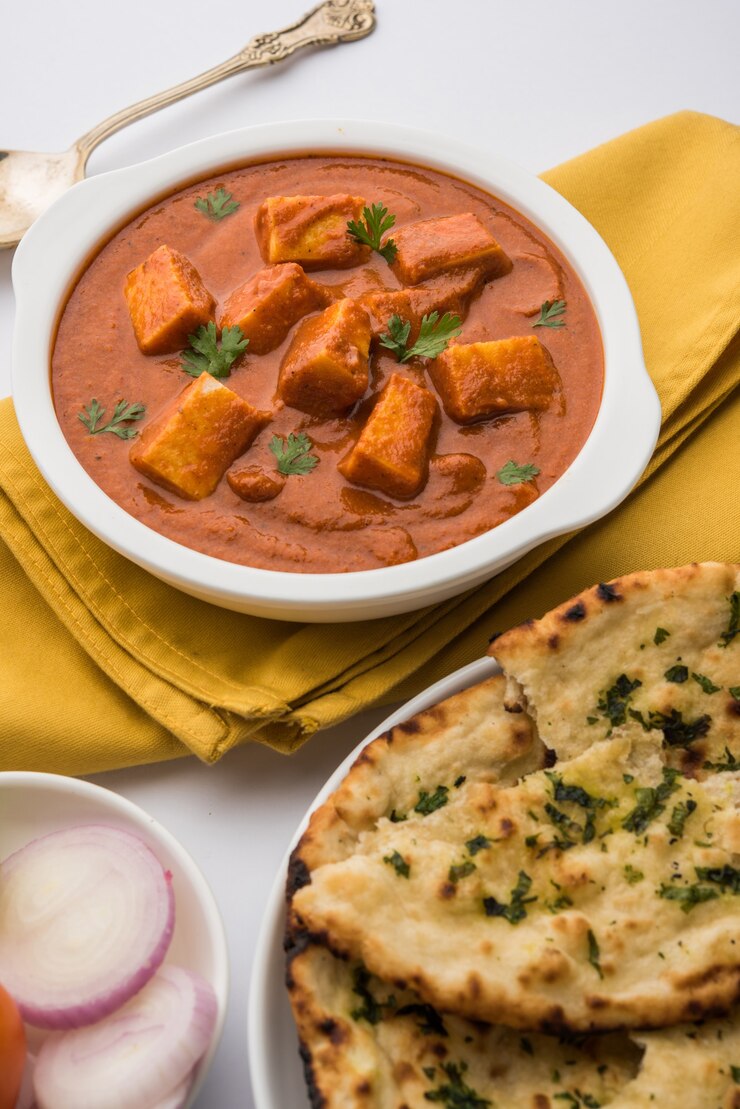 Photo paneer butter masala or cheese cottage curry, popular indian lunch and dinner menu  served in karahi with naan or roti over moody background, selective focus