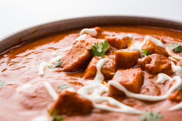 Paneer Butter Masala or Cheese Cottage Curry, popular Indian Lunch and Dinner menu  served in Karahi with Naan Or Roti over moody background, selective focus