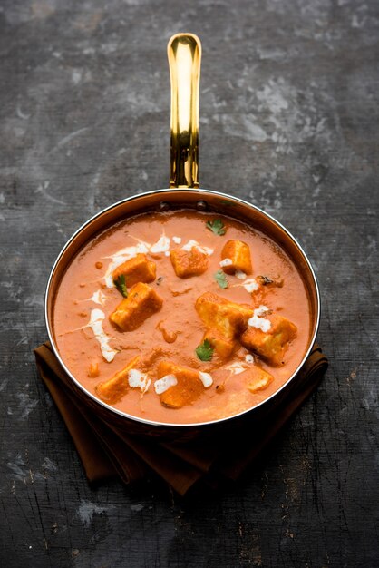 Paneer butter masala or cheese cottage curry in serving a bowl\
or pan, served with or without roti and rice