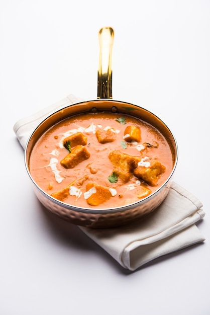 Paneer butter masala or cheese cottage curry in serving a bowl\
or pan, served with or without roti and rice