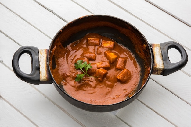 Foto paneer butter masala of cheese cottage curry, populair indiaas lunch- en dinermenu geserveerd in karahi met naan of roti over humeurige achtergrond, selectieve focus