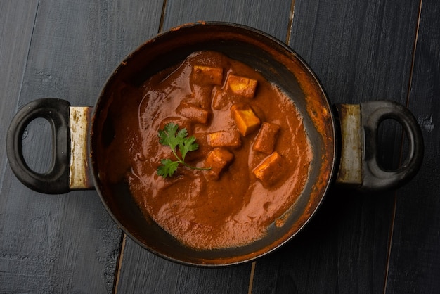 Paneer Butter Masala of Cheese Cottage Curry, populair Indiaas lunch- en dinermenu geserveerd in Karahi met Naan of Roti over humeurige achtergrond, selectieve focus