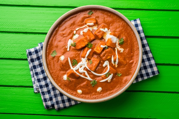 Paneer Butter Masala of Cheese Cottage Curry, populair Indiaas lunch- en dinermenu geserveerd in Karahi met Naan of Roti over humeurige achtergrond, selectieve focus