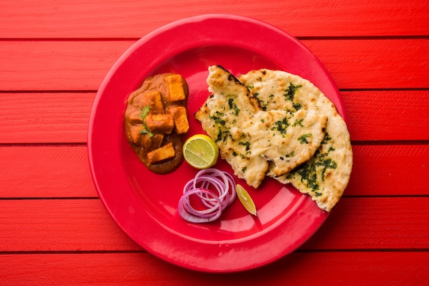 Paneer Butter Masala of Cheese Cottage Curry, populair Indiaas lunch- en dinermenu geserveerd in Karahi met Naan of Roti over humeurige achtergrond, selectieve focus