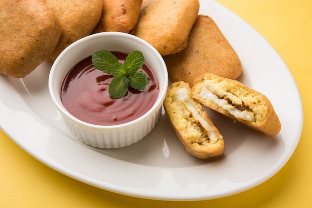 Paneer pakoras 또는 Bhajji는 그램 가루 또는 베산 반죽으로 코팅된 매운 코티지 치즈 큐브입니다. 다채로운 또는 나무 배경 위에 접시에 토마토 케첩과 함께 제공됩니다. 선택적 초점