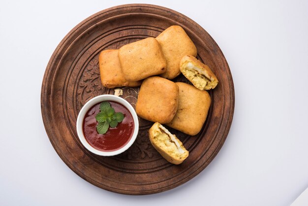 Paneer pakoras of Bhajji zijn grammeel of besan beslag gecoate pittige kwarkblokjes. Geserveerd met tomatenketchup in een bord over kleurrijke of houten achtergrond. Selectieve focus