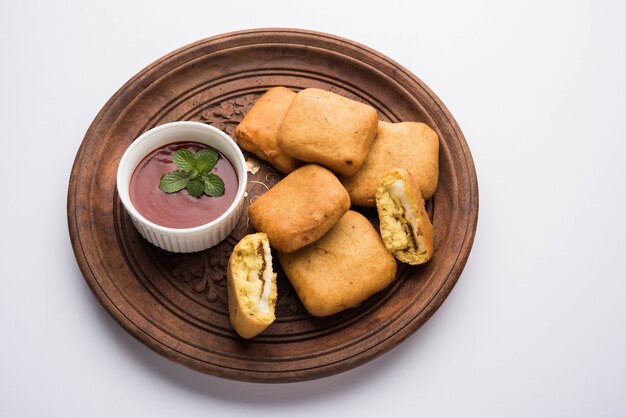 Paneer pakoras of Bhajji zijn grammeel of besan beslag gecoate pittige kwarkblokjes. Geserveerd met tomatenketchup in een bord over kleurrijke of houten achtergrond. Selectieve focus