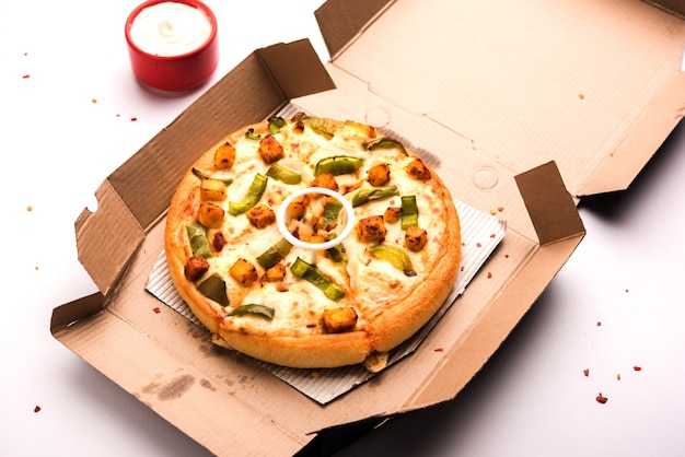 Paneer Pizza는 인도식 이탈리아 요리로 코티지 치즈를 얹고 화이트 소스를 곁들인 접시에 제공됩니다. 선택적 초점