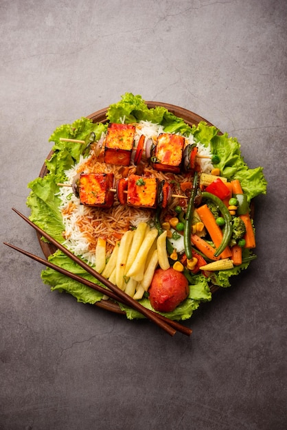 Paneer sizzler è una versione indiana con insalata di ricotta servita sfrigolante su un piatto di pietra caldo