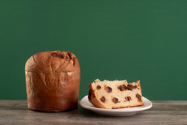 Foto panettone van de de chocoladecake van kerstmis met een plak in een chromaachtergrond of een panetone chocotone