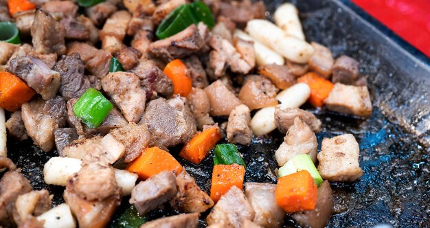 한국 전통 시장에서 Panfried 검은 돼지 고기 식사 당근과 샬롯 파와 함께 맛있는 한국 음식 요리 복사 공간을 닫습니다