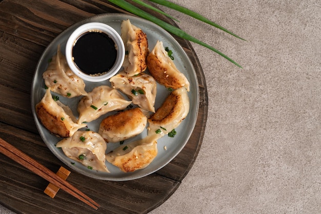 灰色のテーブルの背景に醤油とプレートで餃子餃子をパンフライ