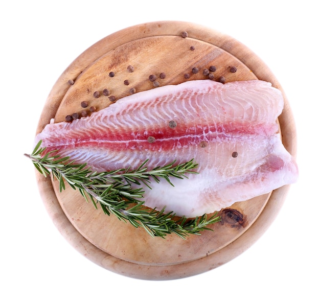 Pangasius fillet on wooden cutting board with pepper and rosemary sprigs isolated on white