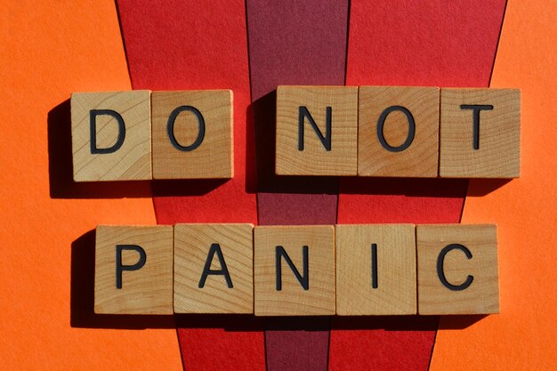 Photo do not panic phrase in wooden alphabet letters isolated on red and orange background