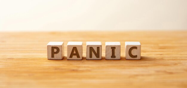 panic text on wooden cube on wooden table background uncontrollable fear overhead view banner