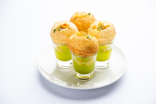 Panipuri Shot или Golgappa Shots с водой разных вкусов, подаваемой в маленьких стаканах с индийской закуской из пури с начинкой