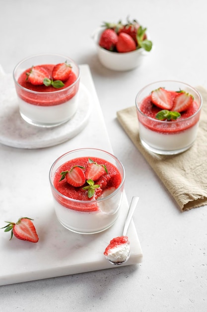 Panna cotta met aardbei in glazen potten versierd met verse bessen en munt Italiaans dessert