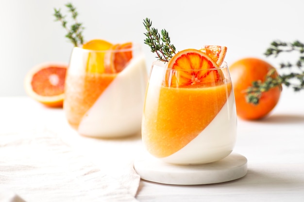 Foto panna cotta oranje desserts versierd met sinaasappels en tijm staan op wit