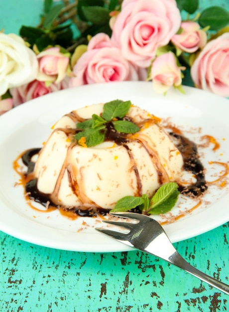 Panna Cotta with chocolate and caramel sauces on color wooden background