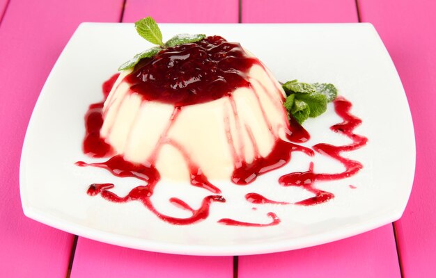 Panna Cotta with raspberry sauce on color wooden background