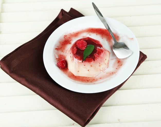 Panna Cotta with raspberry sauce on wooden table