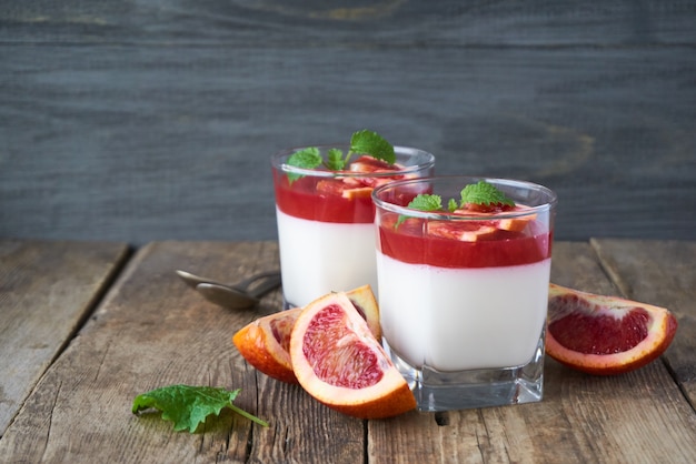 Pannacotta met roodoranje gelei op een houten lijst