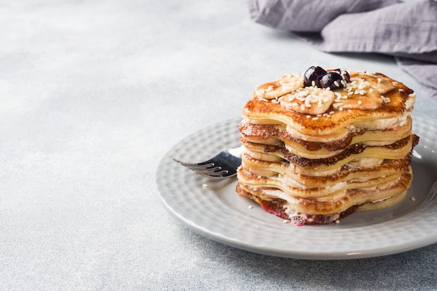 Pannekoekcake met bananen en bessenstroop, selectieve nadruk, grijze achtergrond.