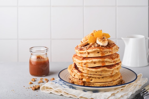 Pannekoeken. Zelfgemaakte pluizige pannenkoek met banaan, walnoot en karamel voor het ontbijt op lichte betonnen ondergrond. Heerlijke pannenkoeken voor traditioneel Amerikaans ontbijt. Selectieve aandacht. Bespotten.