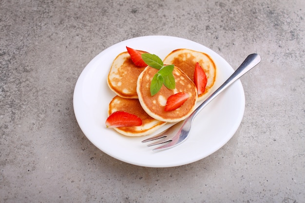 Pannenkoek in een plaat met aardbeien versierd met munt op een betonnen tafel