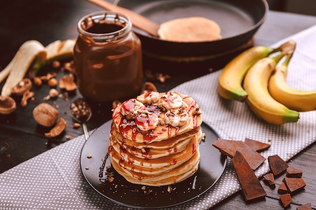 Pannenkoek met chocolade en notenpasta, walnoten en banaan op een zwart bord