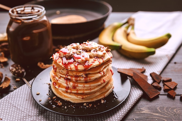 Pannenkoek met chocolade en notenpasta, walnoten en banaan op een zwart bord