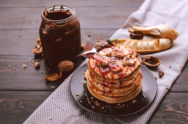 Pannenkoek met chocolade en notenpasta, walnoten en banaan op een zwart bord