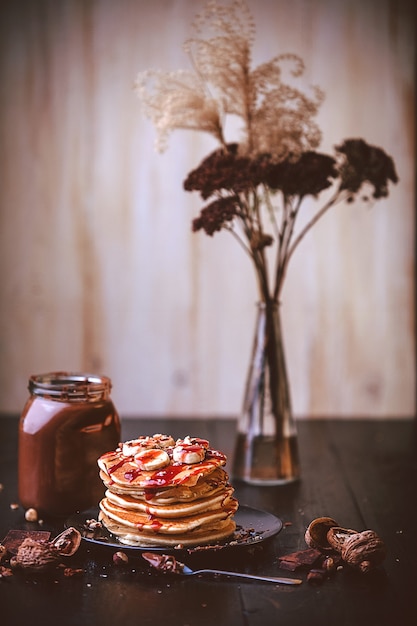 Pannenkoek met chocolade en notenpasta, walnoten en banaan op een zwart bord