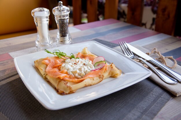 Pannenkoek met zalm en zure room en dille op een witte plaat