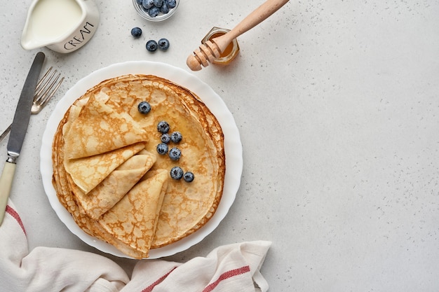 Foto pannenkoeken, dunne pannenkoeken of blini met bessen in witte plaat. bovenaanzicht. pannenkoekenweek. stuk. ruimte voor tekst.